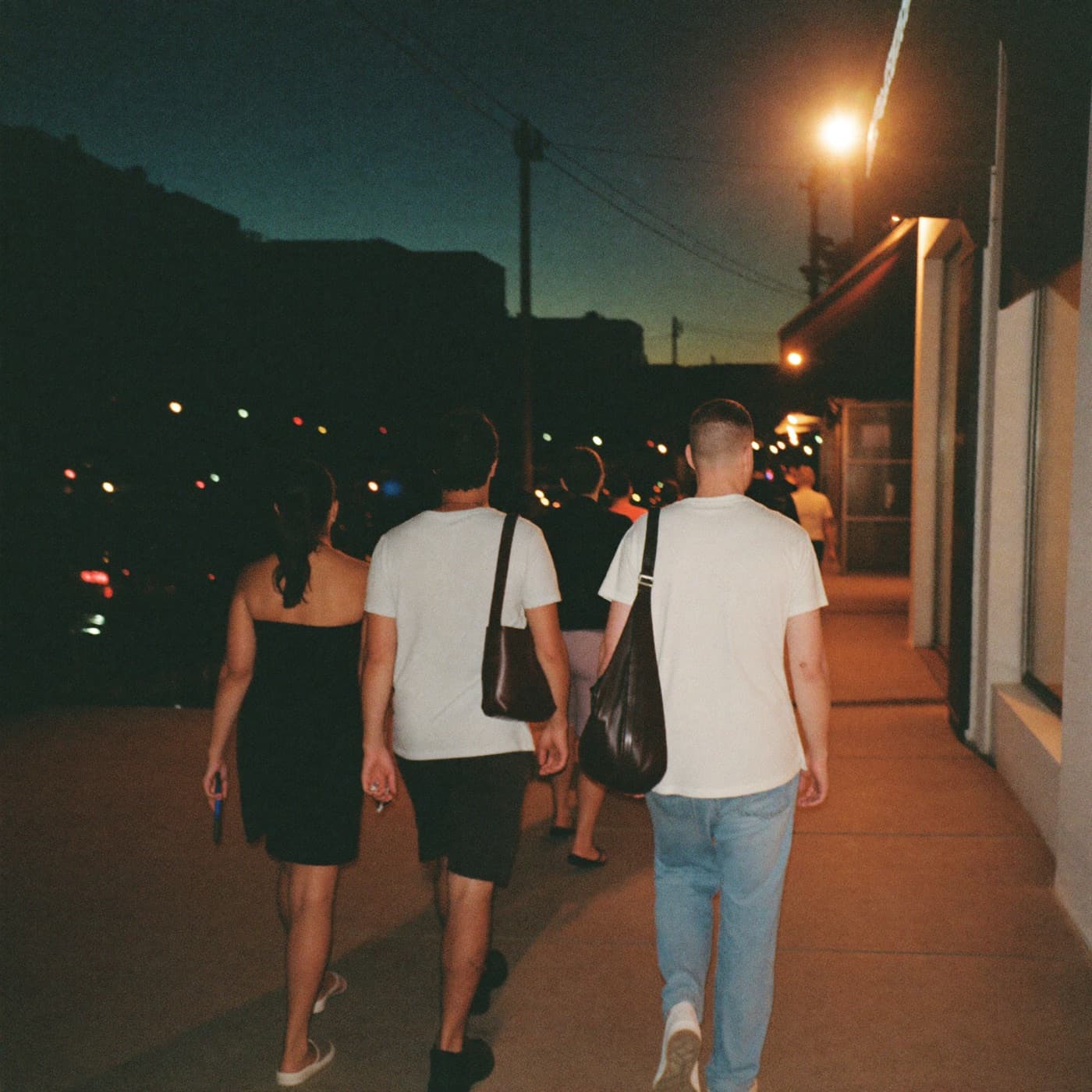 A group of friends walking together along a sidewalk at dusk